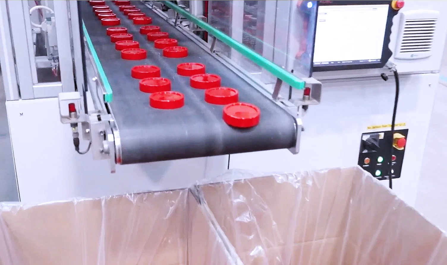Red plastic caps being packed into a box at Axium Packaging