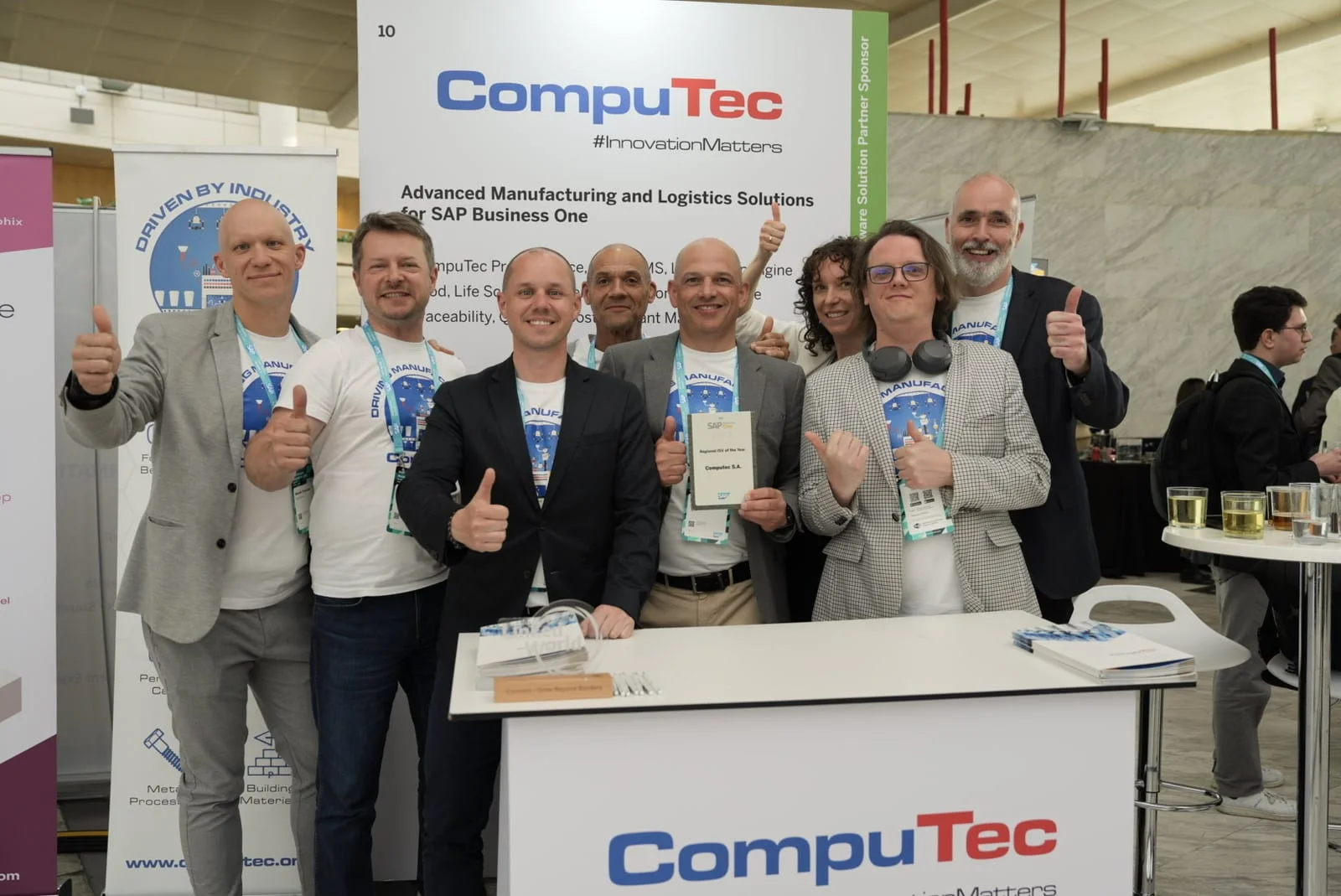 CompuTec team at its stand in Madrid giving a thumbs-up, holding the SAP Regional ISV of the Year award
