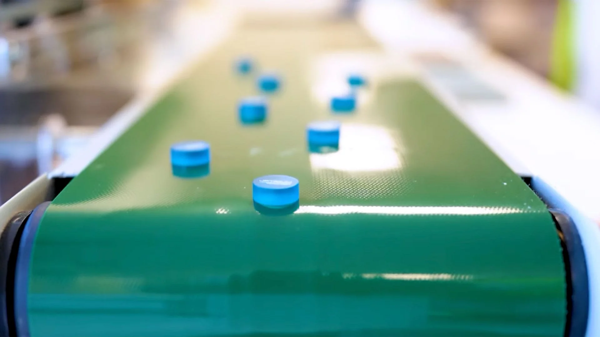 Blue contact lens buttons moving along a conveyor at Contamac's manufacturing facility