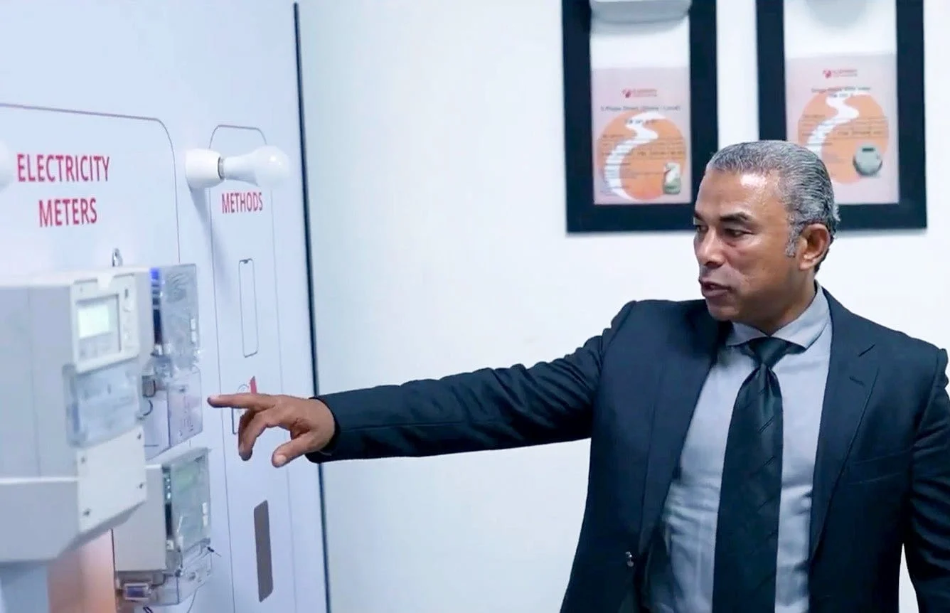 Two El Sewedy Electrometer executives reviewing a wall of electricity meters