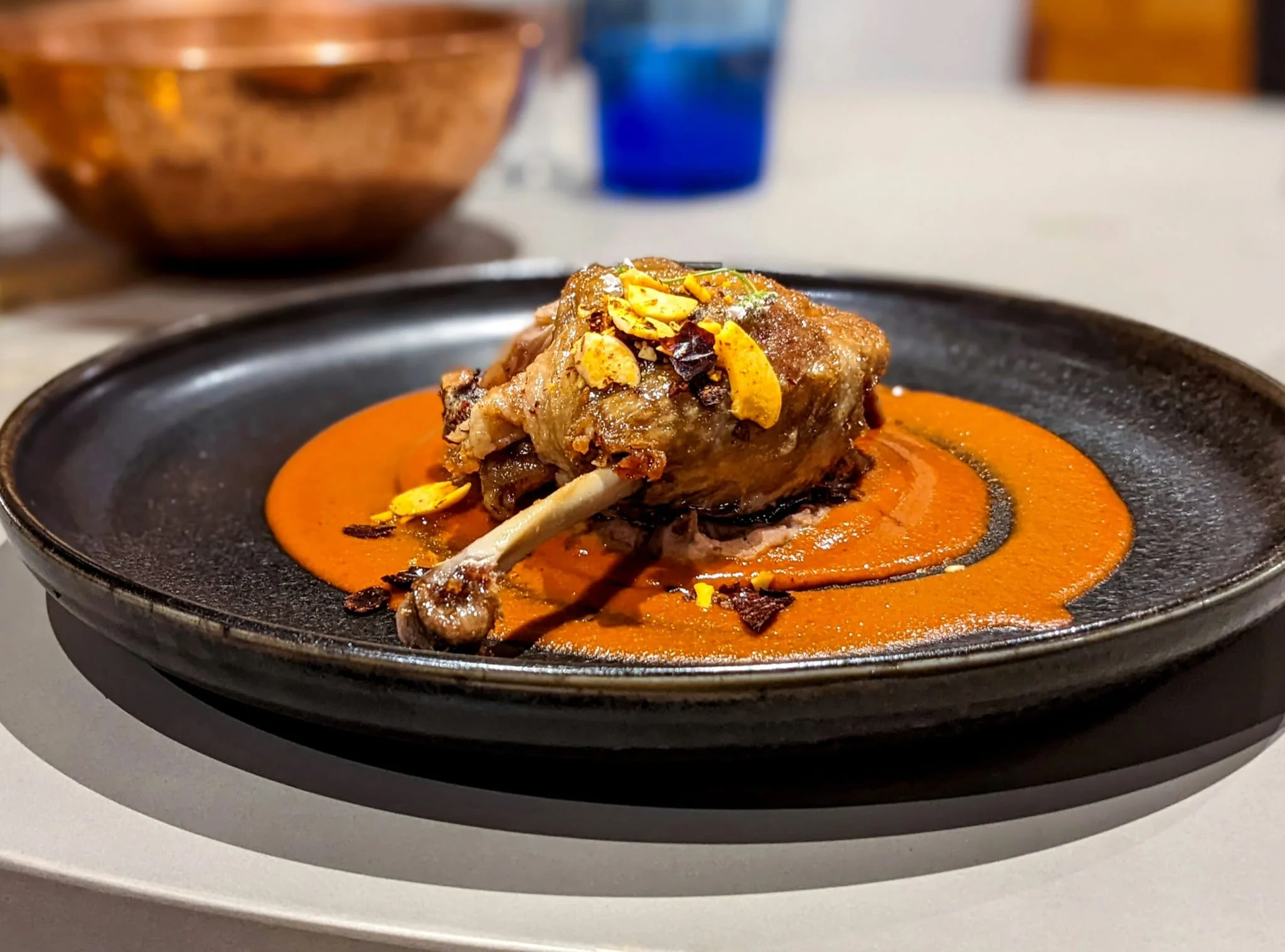A plated duck confit leg with sauce
