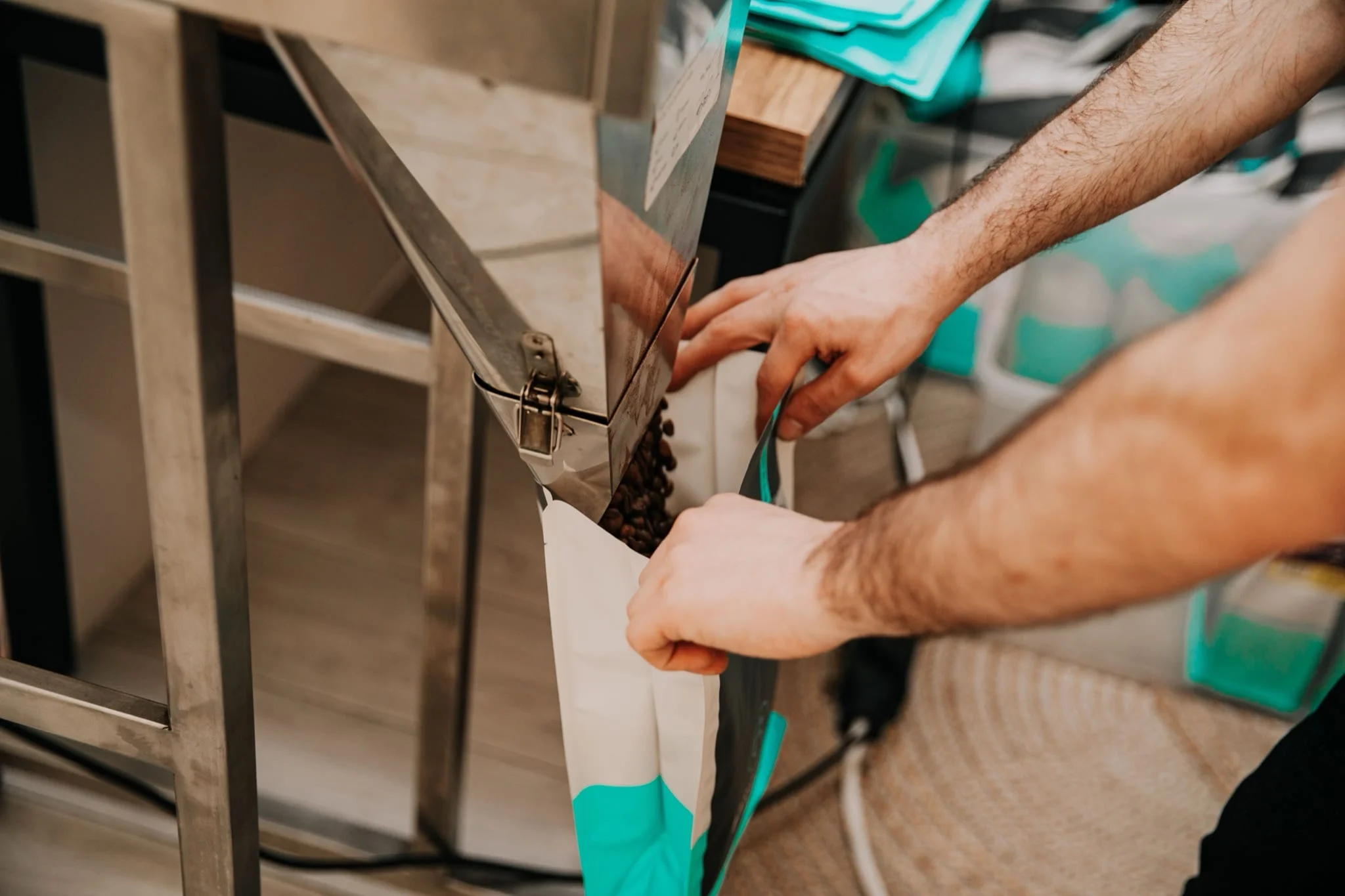 Hands packing coffee beans into a pouch on a production line