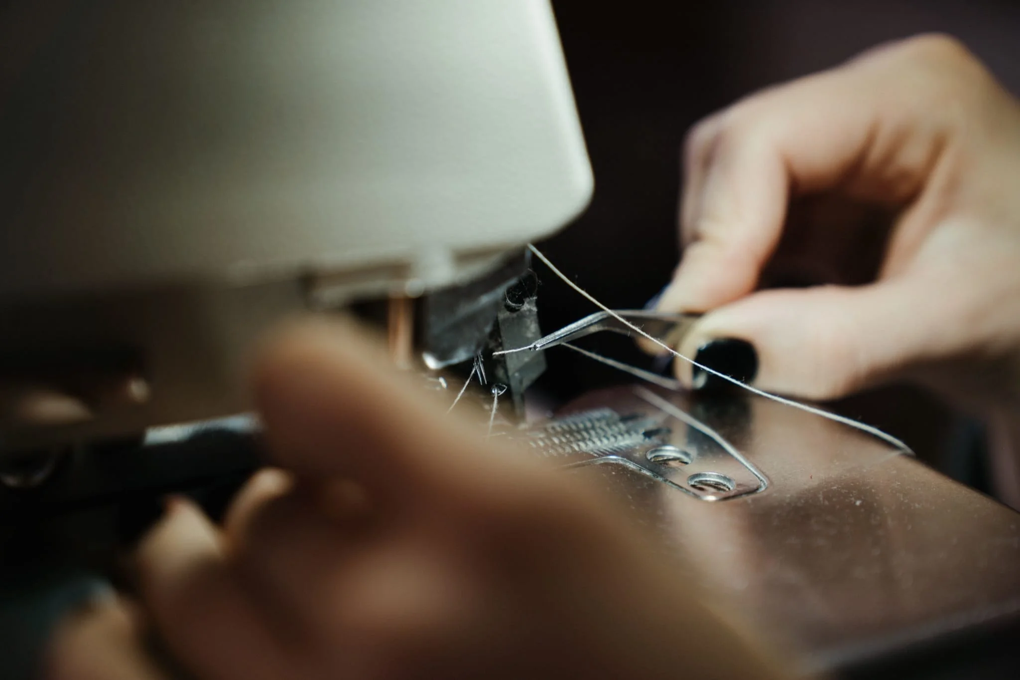 A close-up of hands sewing fabric on an industrial sewing machine