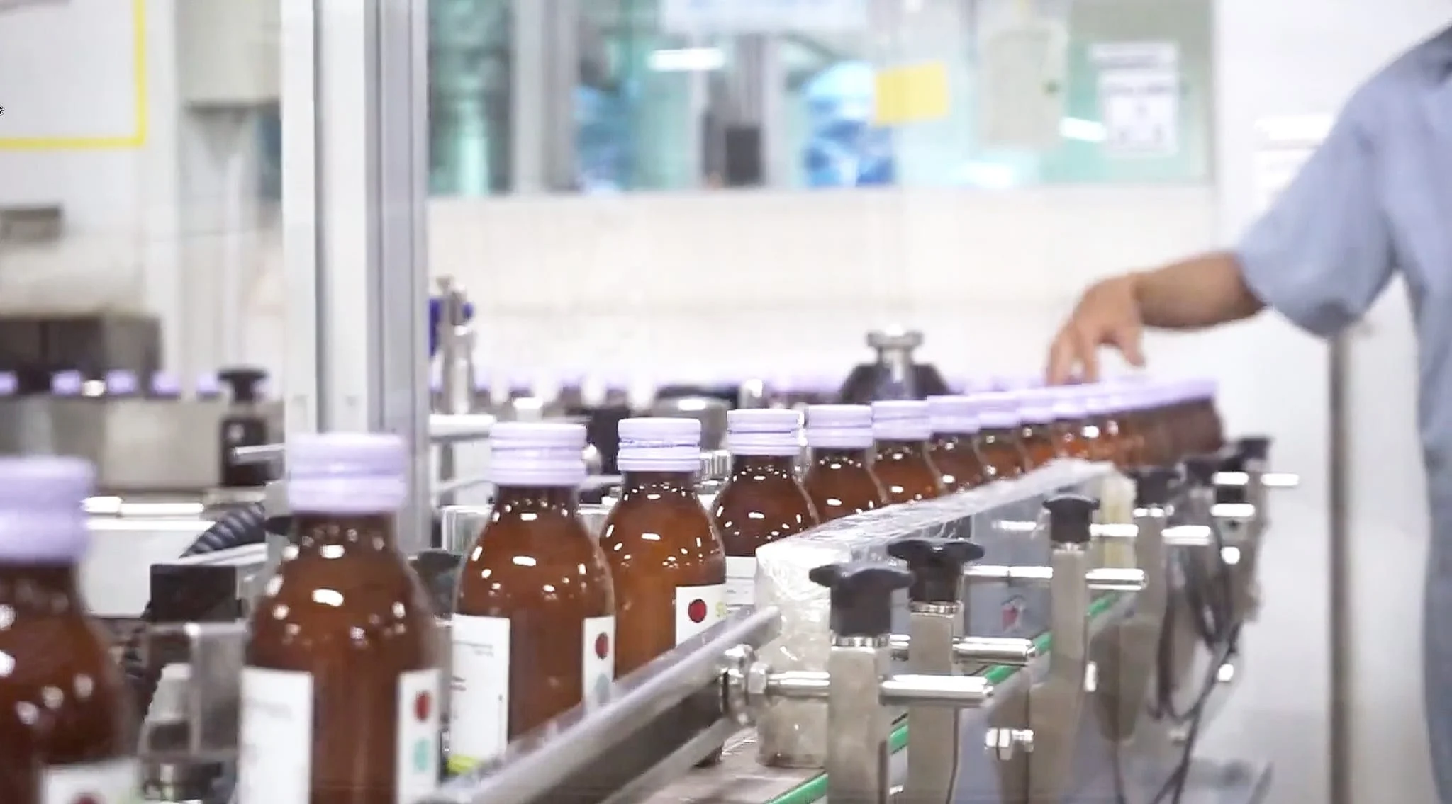 A worker inspecting bottles with lavender caps on Meprofarm's bottling line