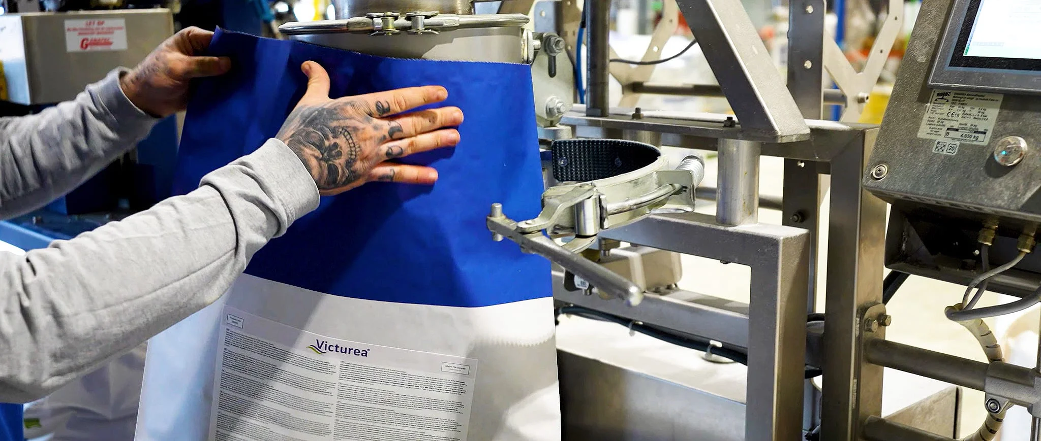 A Palital Feed Additives employee sealing a bag of Victurea coated urea, with a touch screen tracking the line