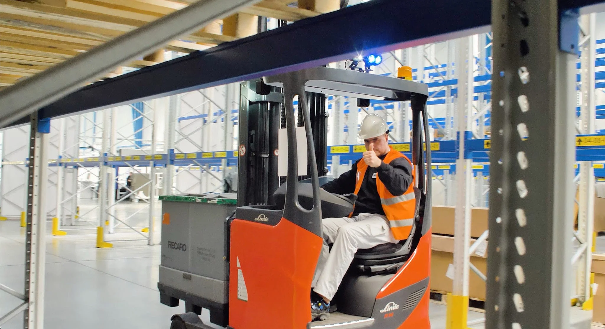 A Schnug Logistic Group forklift operator giving a thumbs up in the warehouse