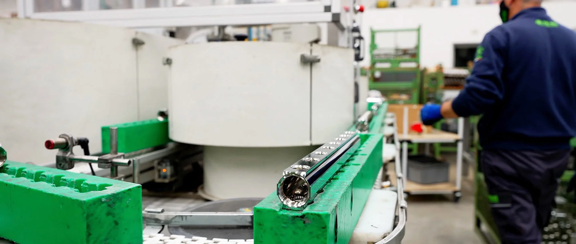 A TE-SA employee carrying a finished chrome manifold assembly across the factory floor