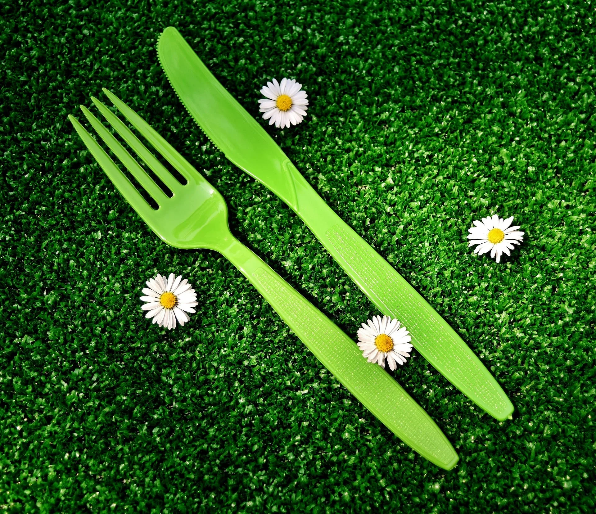 Green plastic cutlery outdoors on grass